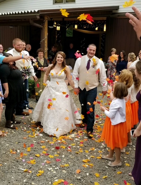 Bride and groom walking down the aisle with flower petals